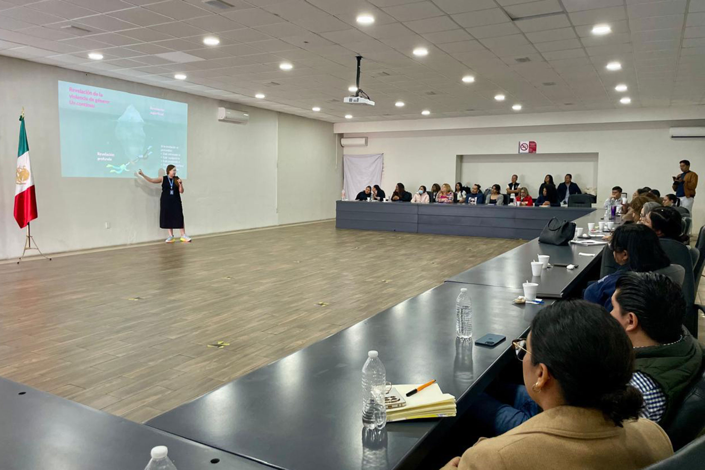A woman stands in a large room, leading a training